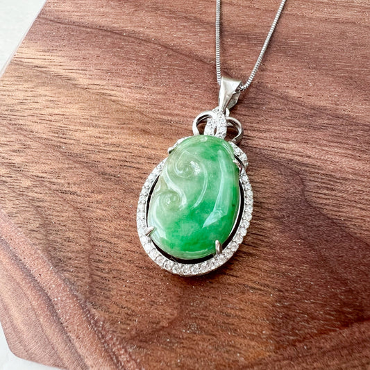 Close-up of green carved jadeite jade ruyi pendant in sterling silver with pavé halo on chain, glossy finish