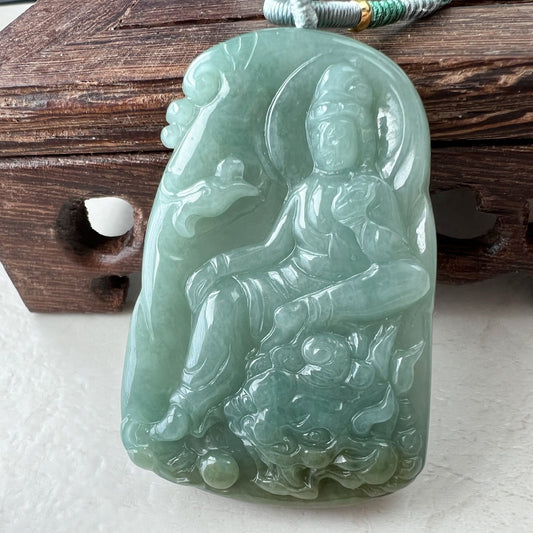 Close-up of semi-translucent green jade Guan Yin pendant with dragon carving and polished glossy finish