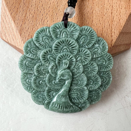 Close-up of large green jadeite peacock carved pendant with glossy finish and intricate layered relief carving